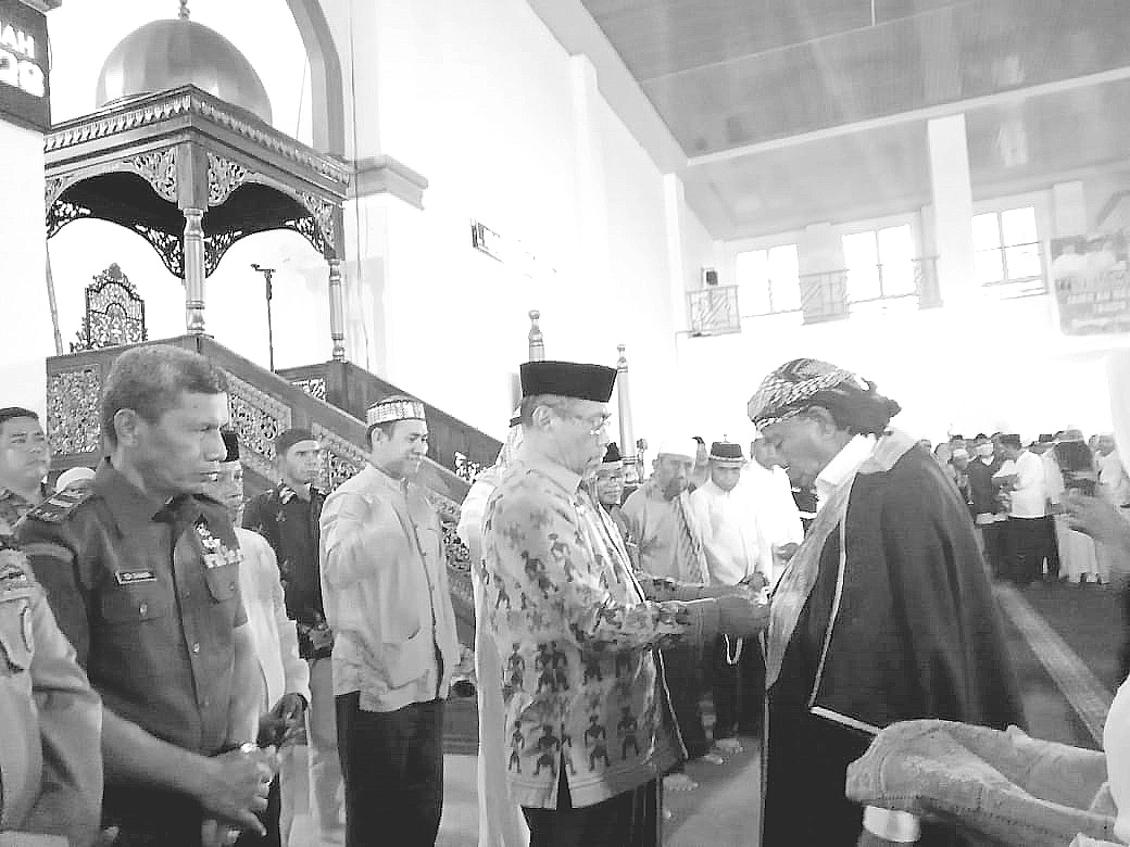 SAMBUT: Wabup Muna Bachrun Labuta memakaikan jubah ke salah satu jemaah haji asal Muna di Masjid Al Munajat, kemarin.