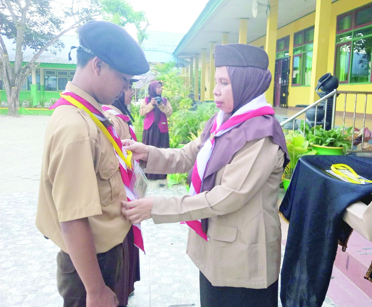 Kepala SMAN 2 Kendari, Nur Aida, S.Pd , menyematkan kalung tanda peserta kepada perwakilan anggota baru. (Ewin Endang Sahputri/Kendari Pos)