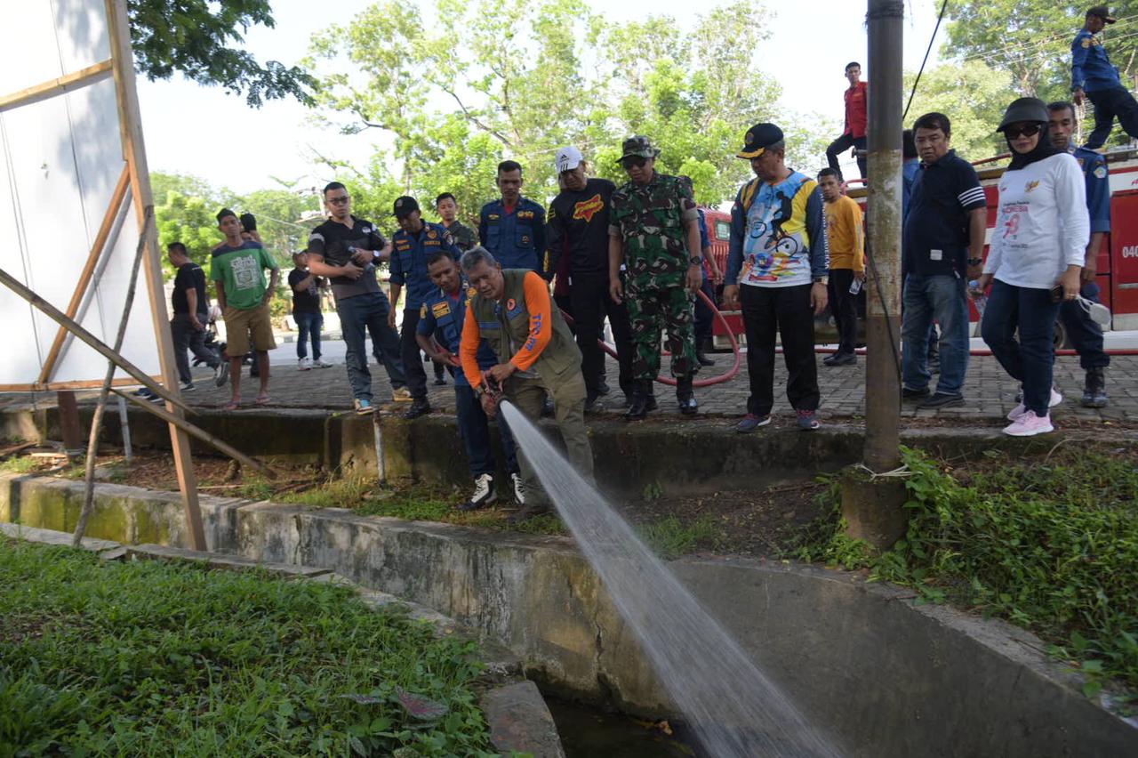 Pj Wali Kota Kendari Muh Yusup (depan) berbekal selang pemadam kebakaran berusaha mengurai drainase yang tersumbat di kawasan Kecamatan Mandong dalam gerakan bersih-bersih lingkungan bersama ASN dan personel Kodim Kendari, Jumat Jumat (29/12/2023). (AGUS SETIAWAN / KENDARI POS)