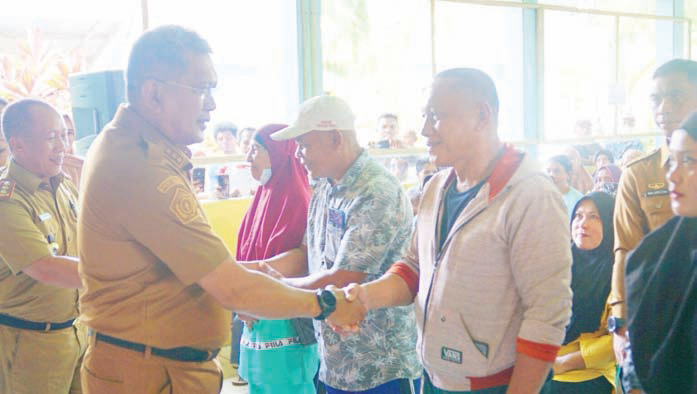 Ketgam : Pj Wali Kota Kendari, Muhammad Yusup (dua dari kiri) didampingi Kepala Disketapang Kota Kendari, Abdul Rauf (kiri) menyalami warga ketika peluncuran penyaluran bantuan pangan di Kelurahan Watulondo kemarin. (AGUS SETIAWAN/KENDARI POS)