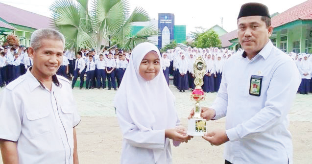 Penyerahan piala kepada Raihanah Rohadatul Aisy (tengah), sebagai juara I lomba Musabaqoh Hifdzil Quran (MHQ) cabang 10 Juz putri Tingkat Kota Kendari. (MTSN 1 KENDARI)