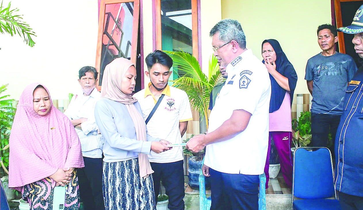 BANTUAN KORBAN BANJIR : Pj Wali Kota Kendari, Muhammad Yusup (kanan) menyerahkan santunan kepada keluarga Almarhumah Fani (2) korban banjir di Kelurahan Bende, kemarin. (GUS SETIAWAN/KENDARI POS)