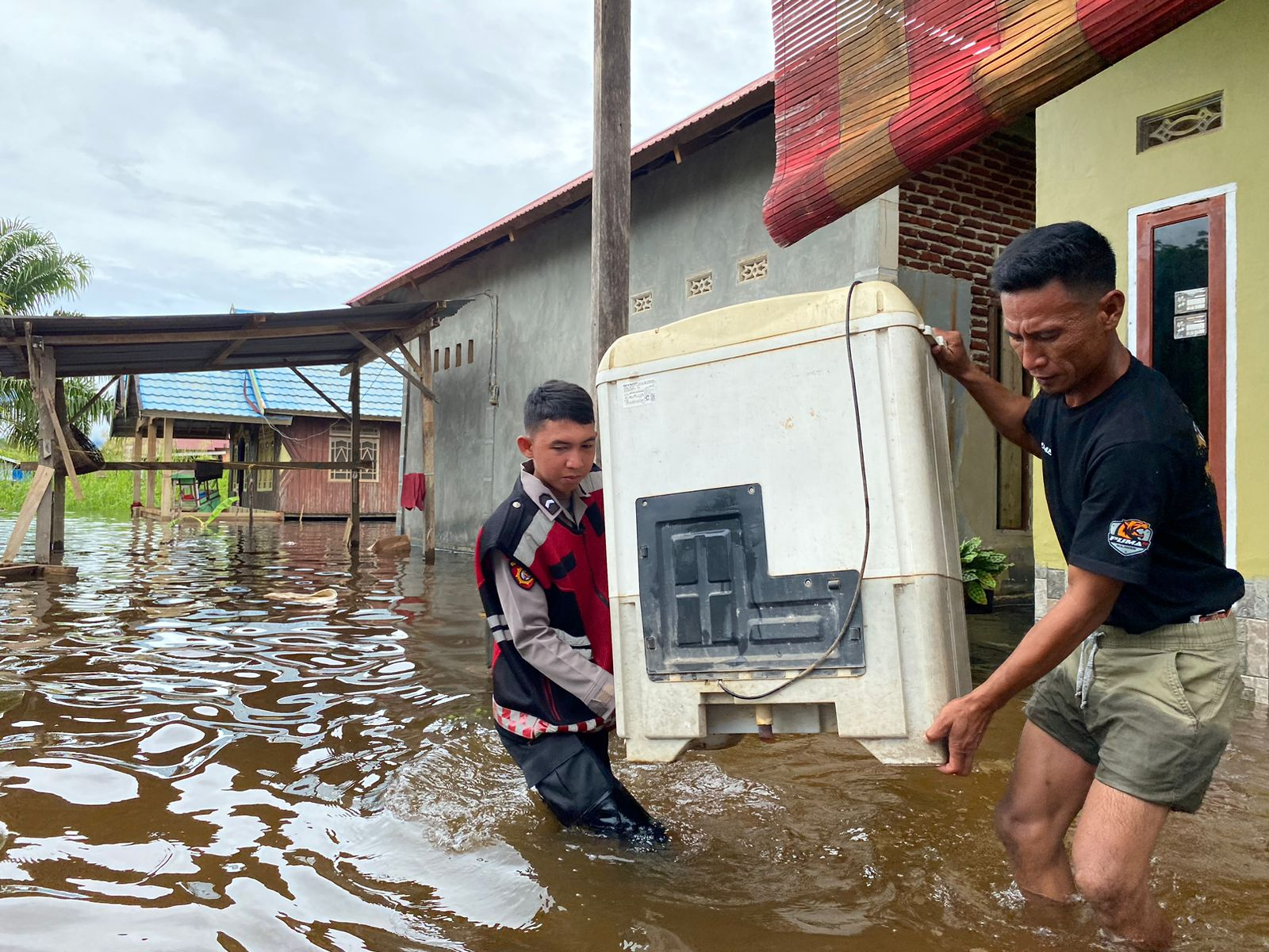 Warga Konut yang terdampak banjir dibantu personel Polres Konut (kiri) berusaha menyelamatkan barang berharga akibat meluapnya air sungai dari curah hujan yang sangat tinggi, Kamis (9/5/2024). (HELMIN TOSUKI / KENDARI POS)