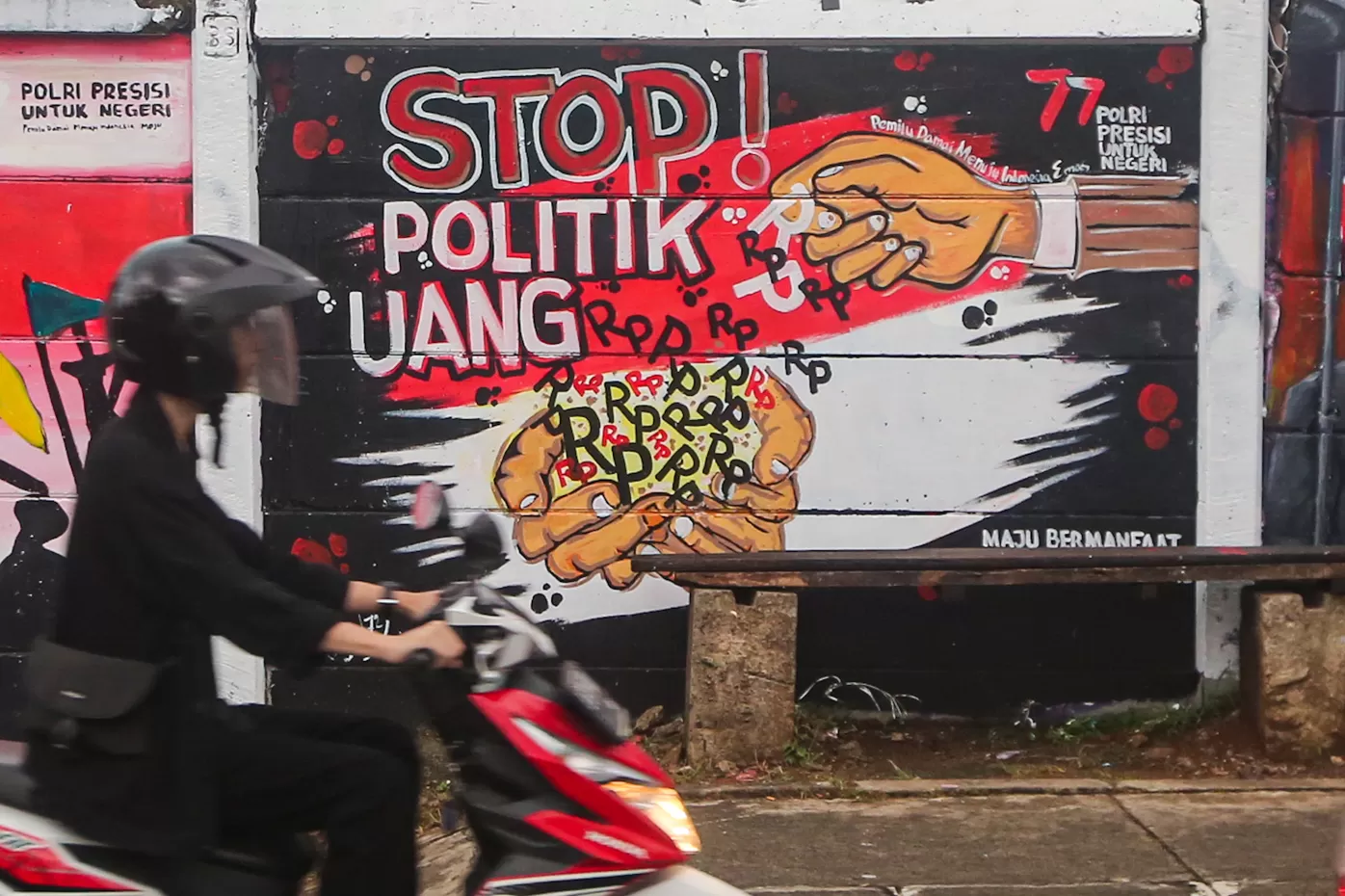 Warga melintas di depan mural pemilu di Margonda, Depok, Jawa Barat. Mural tersebut berisakan pesan pemilu damai dan tolak politik uang. (SALMAN TOYIBI/JAWA POS)