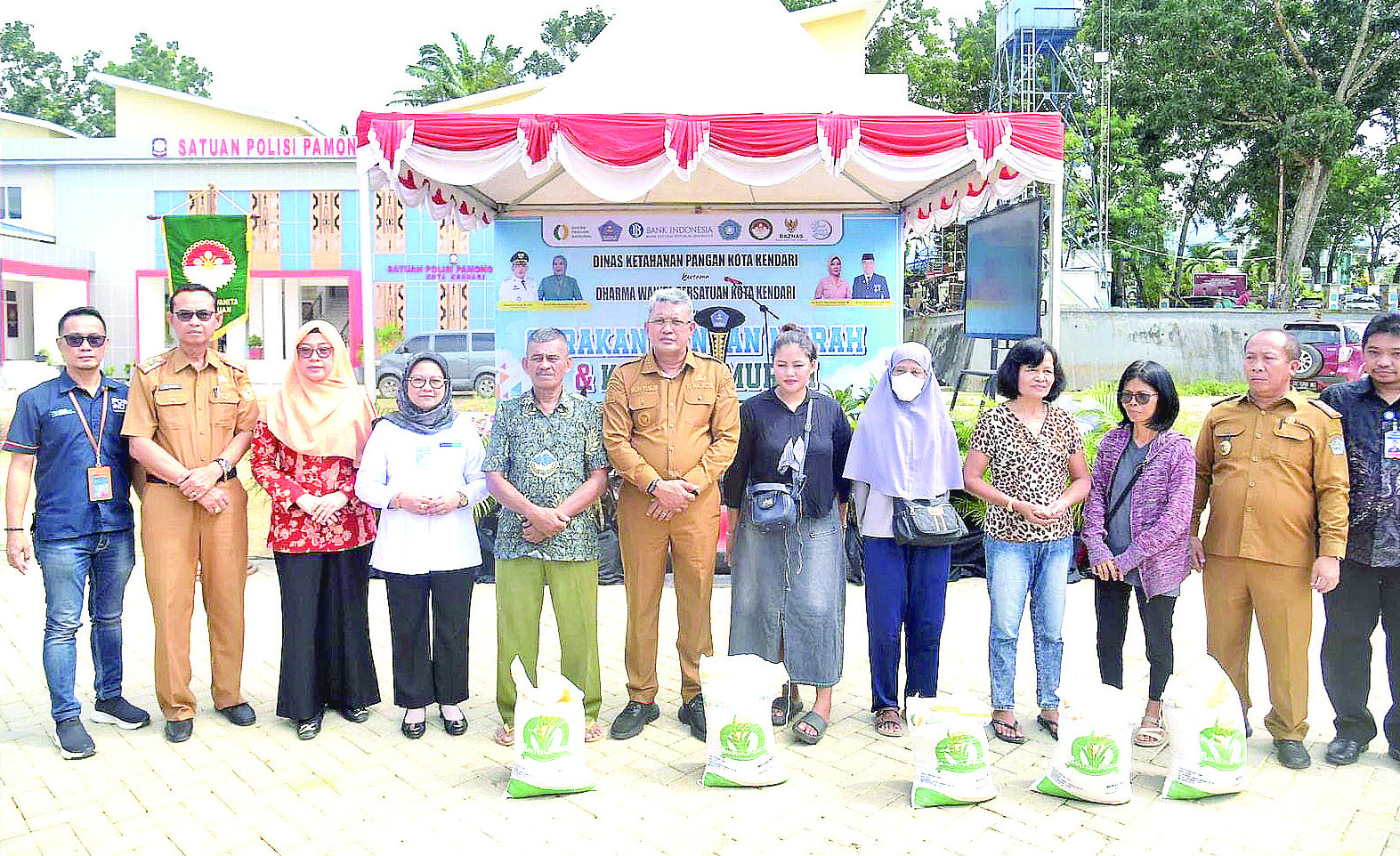 BANTUAN: Pj Wali Kota Kendari, Muhammad Yusup (enam dari kiri) foto bersama warga usai menyerahkan bantuan beras CPP di Pelataran Balai Kota Kendari. (Agus Setiawan/Kendari Pos)