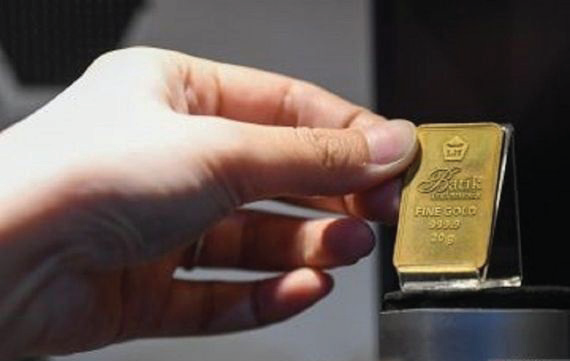 Petugas menunjukkan emas Antam di Butik Antam Pulo Gadung, Jakarta.