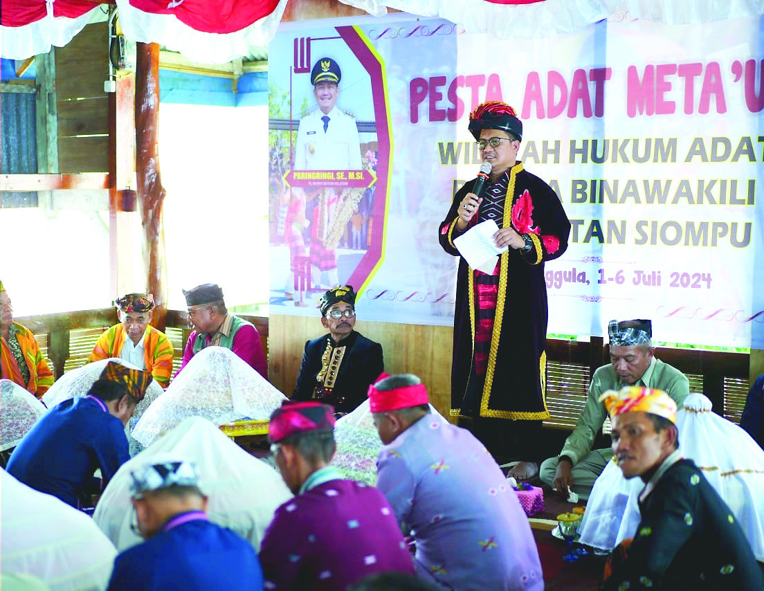 KUNJUNGAN: Pj Bupati Buton Selatan (Busel), Parinringi (berdiri) menjemput aspirasi sekaligus memenuhi undangan warga Siompu yang menggelar pesta adat Mata’u’a Sabtu (5/7/2024). Tampak dia sedang memberikan sambutan. (Elyn/Kendari Pos)