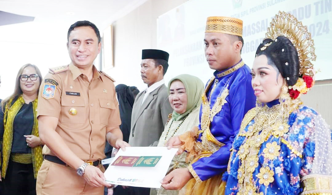 ISBA NIKAH : Pj Sekretaris Kabupaten Kolaka, Muhammad Fadlansyah (kiri) menyerahkan buku nikah kepada salah satu pasangan yang mengikuti nikah massal, kemarin.(PROKOPIM SETKAB KOLAKA FOR KENDARI POS)