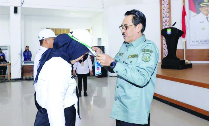 ORIENTASI: Pj Bupati Bombana, Edy Suharmanto (kanan) memakaikan topi dan id card kepada perwakilan peserta, saat pembukaan orientasi PPPK Kabupaten Bombana 2024, Rabu (24/7/2024).(MASLINDAH/KENDARIPOS)