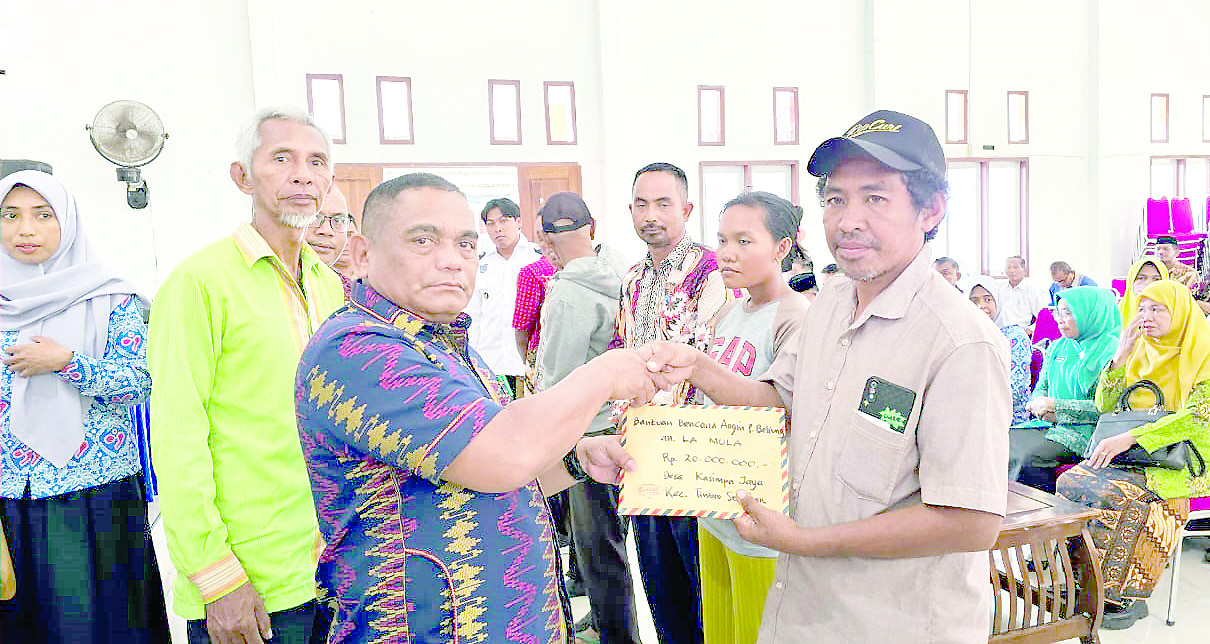 Pj Bupati Mubar, La Ode Butolo (kiri) didampingi Kalak BPBD Mubar, Karimin (baju hijau) menyerahkan bantuan uang tunai kepada korban bencana.(AKHIRMAN/KENDARI POS )