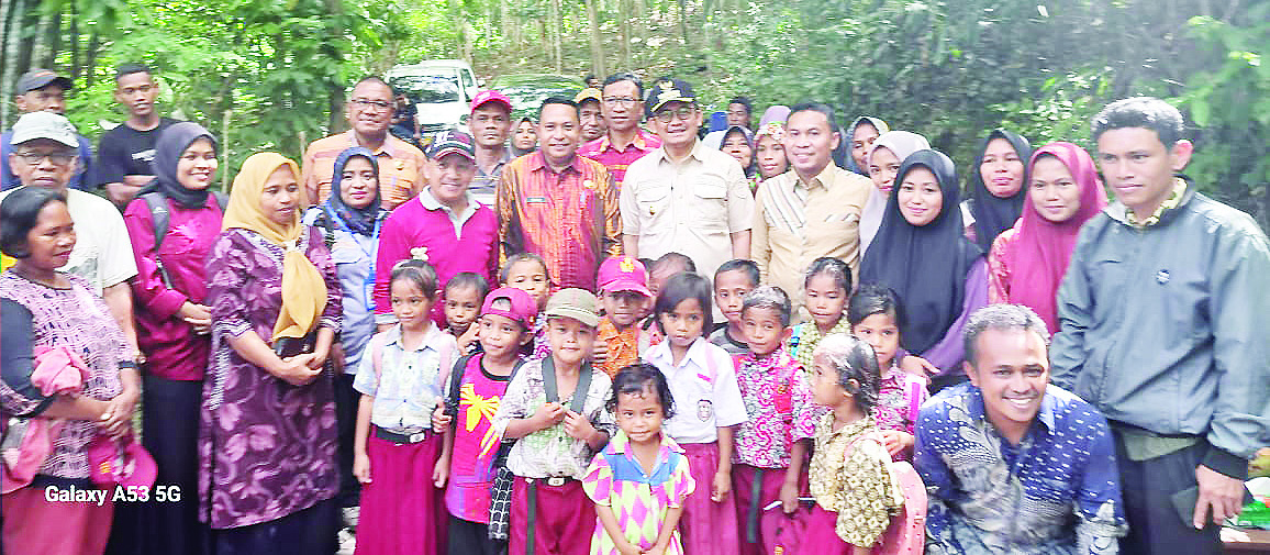 DISAMBUT HANGAT: Pj Bupati Busel, Parinringi (tengah, pakai topi dan kaca mata) didampingi sejumlah Kepala OPD dan anggota DPRD Busel, foto bersama anak-anak dan warga Makolona, Kelurahan Jaya Bakti, Kecamatan Sampolawa, Kamis (1/8/2024). Parinringi rela jalan kaki menyusuri hutan untuk sampai ke dusun tersebut. (ELYN/KENDARI POS)