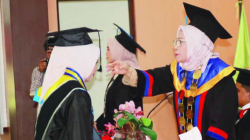 Ketua STIKES Pelita Ibu Kendari, Dra. Hj. Rosmawati Ibrahim, SST., MS., M.Kes (kanan), saat memindahkan tali toga salah satu wisudawati. (EWIN ENDANG SAHPUTRI/KENDARI POS)