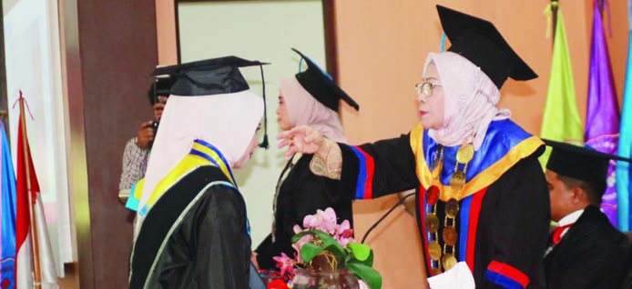 Ketua STIKES Pelita Ibu Kendari, Dra. Hj. Rosmawati Ibrahim, SST., MS., M.Kes (kanan), saat memindahkan tali toga salah satu wisudawati. (EWIN ENDANG SAHPUTRI/KENDARI POS)