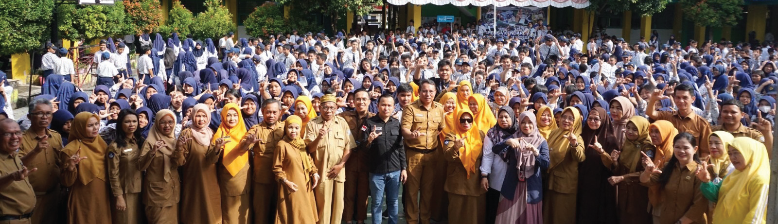 Wakil Direktur Kendari Pos, Awal Nurjadin (tengah, kemeja hitam), Staf Mobile Consumer Operations Territory (MCOT) Telkomsel Kendari, Sandra (6 dari kanan), Kepala SMPN 1 Kendari, Abdul Hamid (9 dari kanan) bersama para guru dan siswa SMPN 1 Kendari menunjukkan gestur Salam Literasi dalam acara road to school, Selasa (22/10/2024).(MUH.ABDI ASMAUL AMRIN / KENDARI POS)