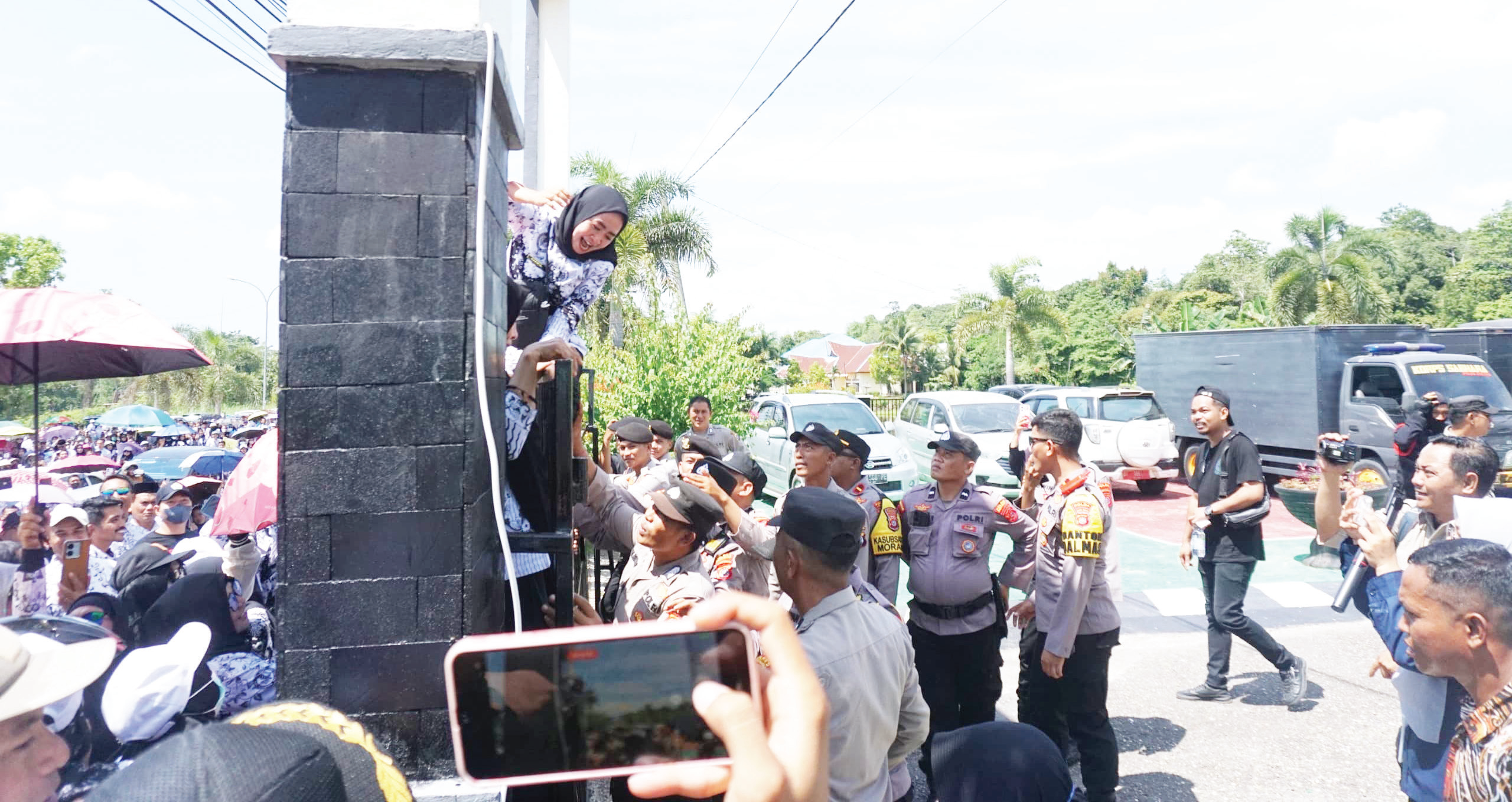 Salah seorang guru memaksa masuk halaman PN Andoolo dengan memanjat pagar dalam aksi demonstrasi menuntut pembebasan Guru Honorer SDN 4 Baito Konawe Selatan, Supriyani dari jeratan hukum, Kamis (24/10/2024). (MUH. ABDI ASMAUL AMRIN/ KENDARI POS)