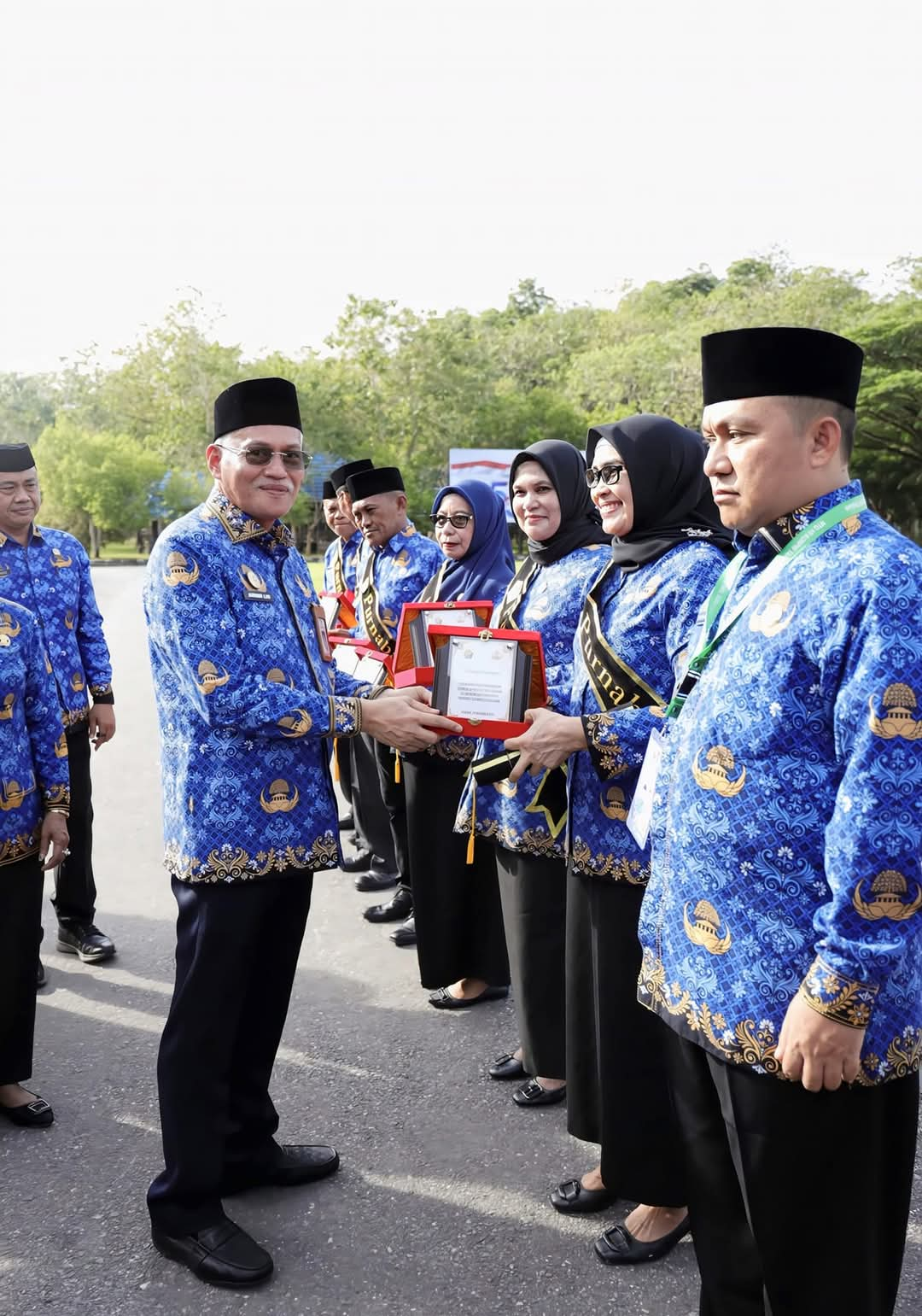 HUMAS PEMPROV SULTRA Sekda Sultra Asrun Lio (kiri) memberikan cendera mata kepada PNS yang memasuki masa purna bakti usai upacara peringatan HUT ke-53 Korpri di pelataran kantor Gubernur Sultra, Jumat (29/11/2024).