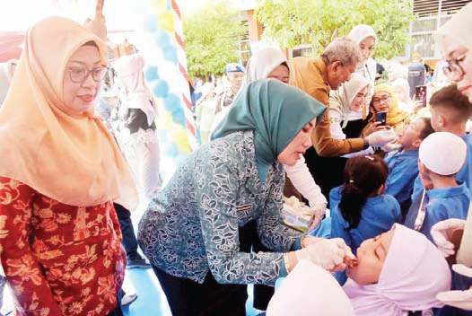 Ketua Tim Penggerak PKK Kota Kendari, Ira Willis Kesumadoty meneteskan vaksin polio kepada salah satu murid SD di Kota Kendari. (IST)