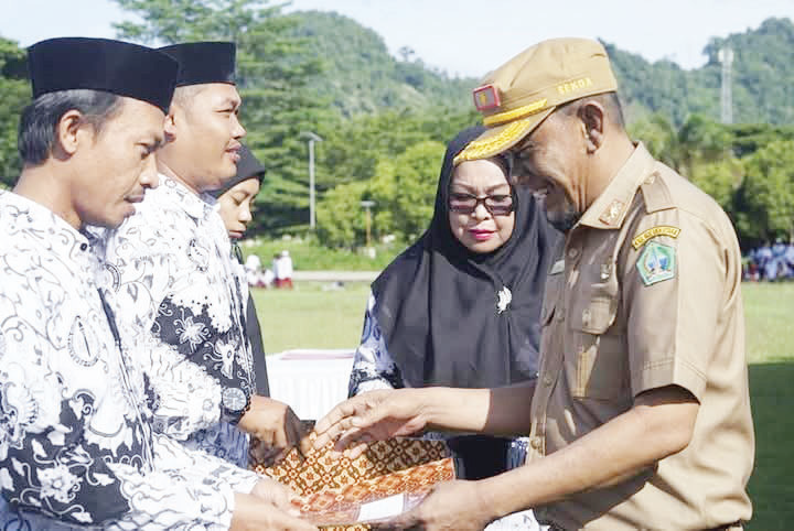 HARI GURU NASIONAL : Sekda Kolut Taupiq menyerahkan penghargaan kepada guru pada peringatan hari guruj nasional di lapangan Aspirasi Lasusua, Senin (25/11)