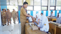 MAKAN GRATIS BERGIZI : Pj Bupati Kolut Yusmin menyalami seorang siswi SMPN 5 Kolut ketika menggelar makan gratis bergizi di kecamatan Batu Putih akhir pekan lalu.