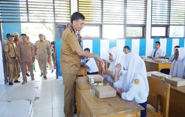 MAKAN GRATIS BERGIZI : Pj Bupati Kolut Yusmin menyalami seorang siswi SMPN 5 Kolut ketika menggelar makan gratis bergizi di kecamatan Batu Putih akhir pekan lalu.